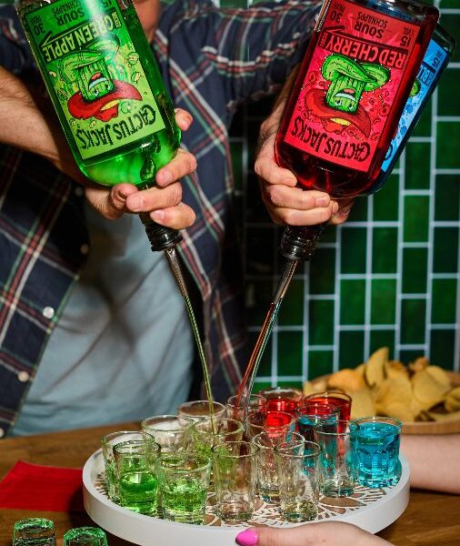 a man pouring three cactus drinks into shot glasses
