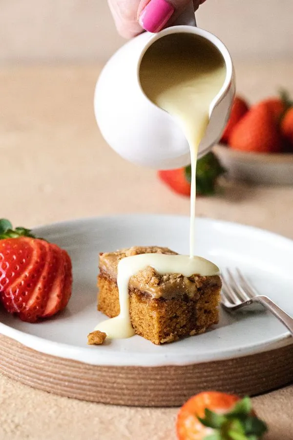 a sticky coffee cake with cream being poured over it