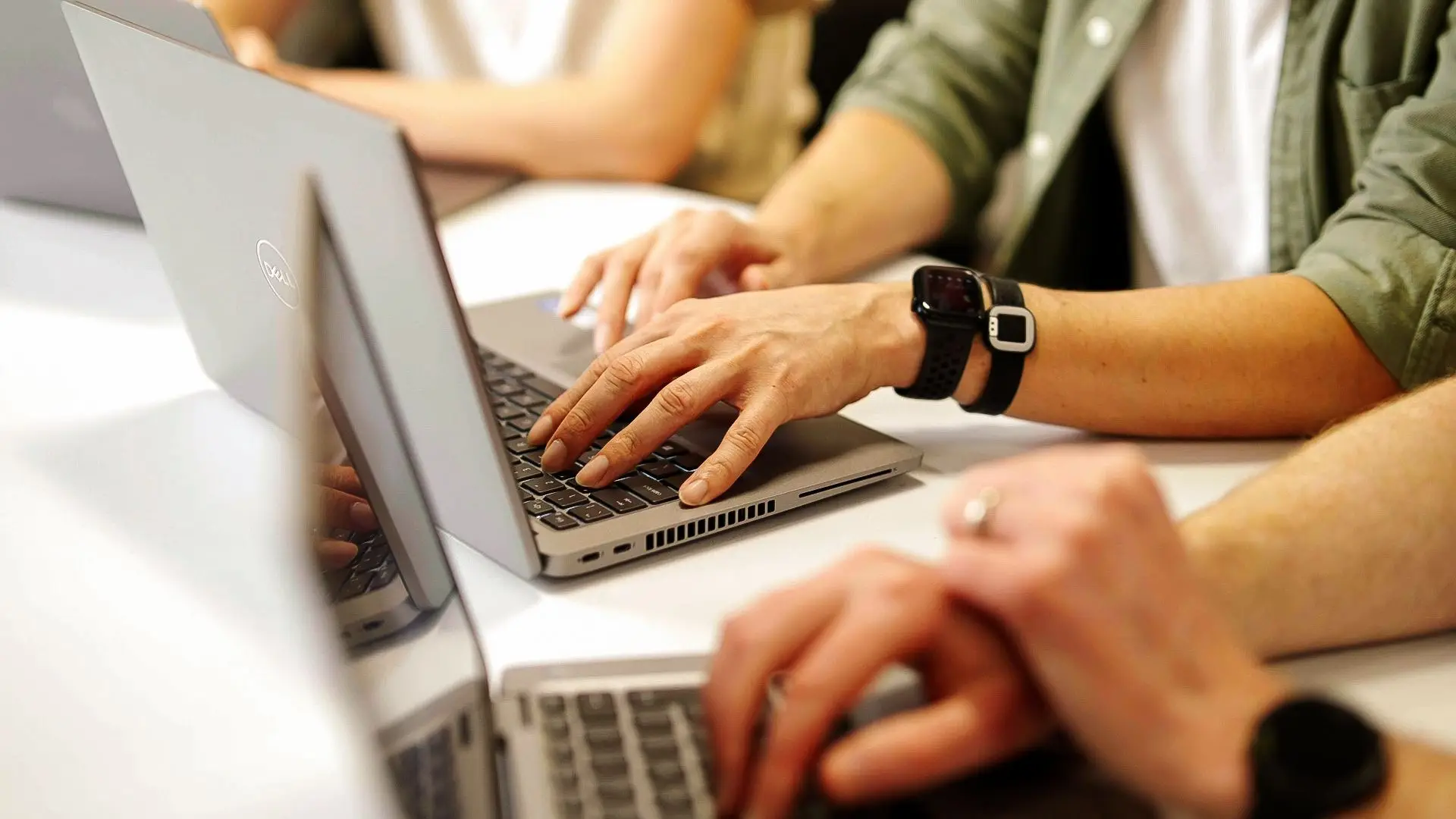 Hands typing on laptops in meeting